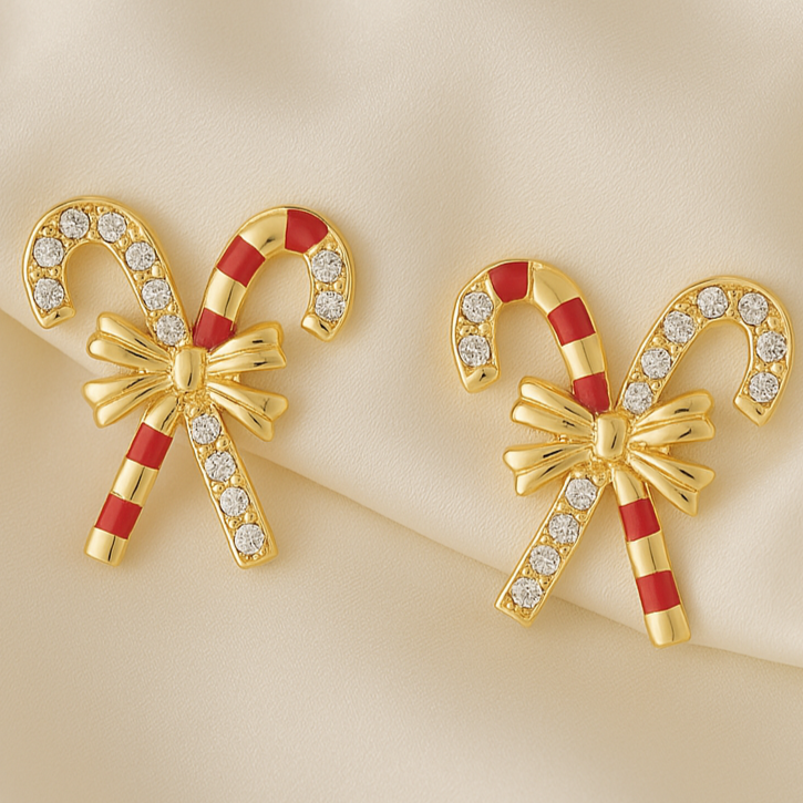 Gold candy cane earrings with red stripes and bow details on a beige background