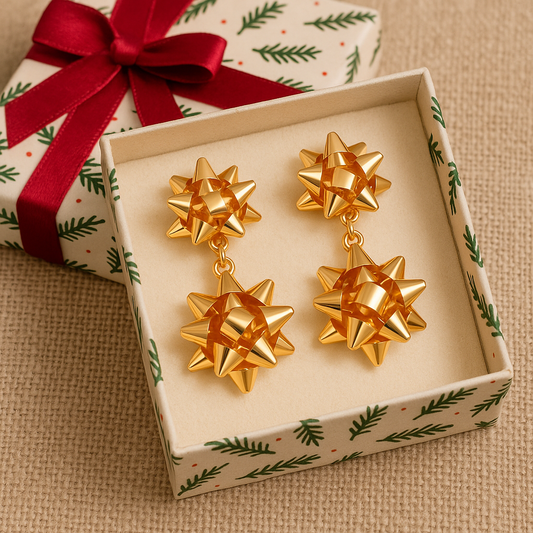 Gold bow-shaped earrings in a decorative box with a Christmas-themed ribbon.
