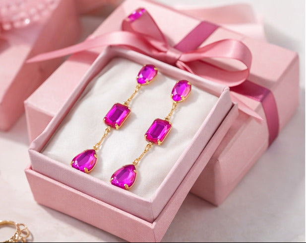 Collage of pink earrings on a woman, in an open box, and on a white surface with a perfume bottle.