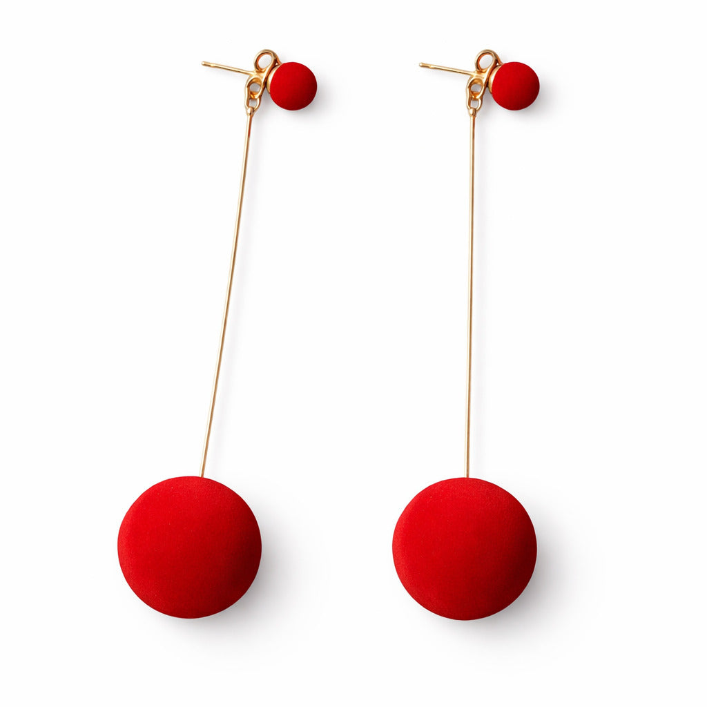 Red spherical earrings on gold hooks against a white background