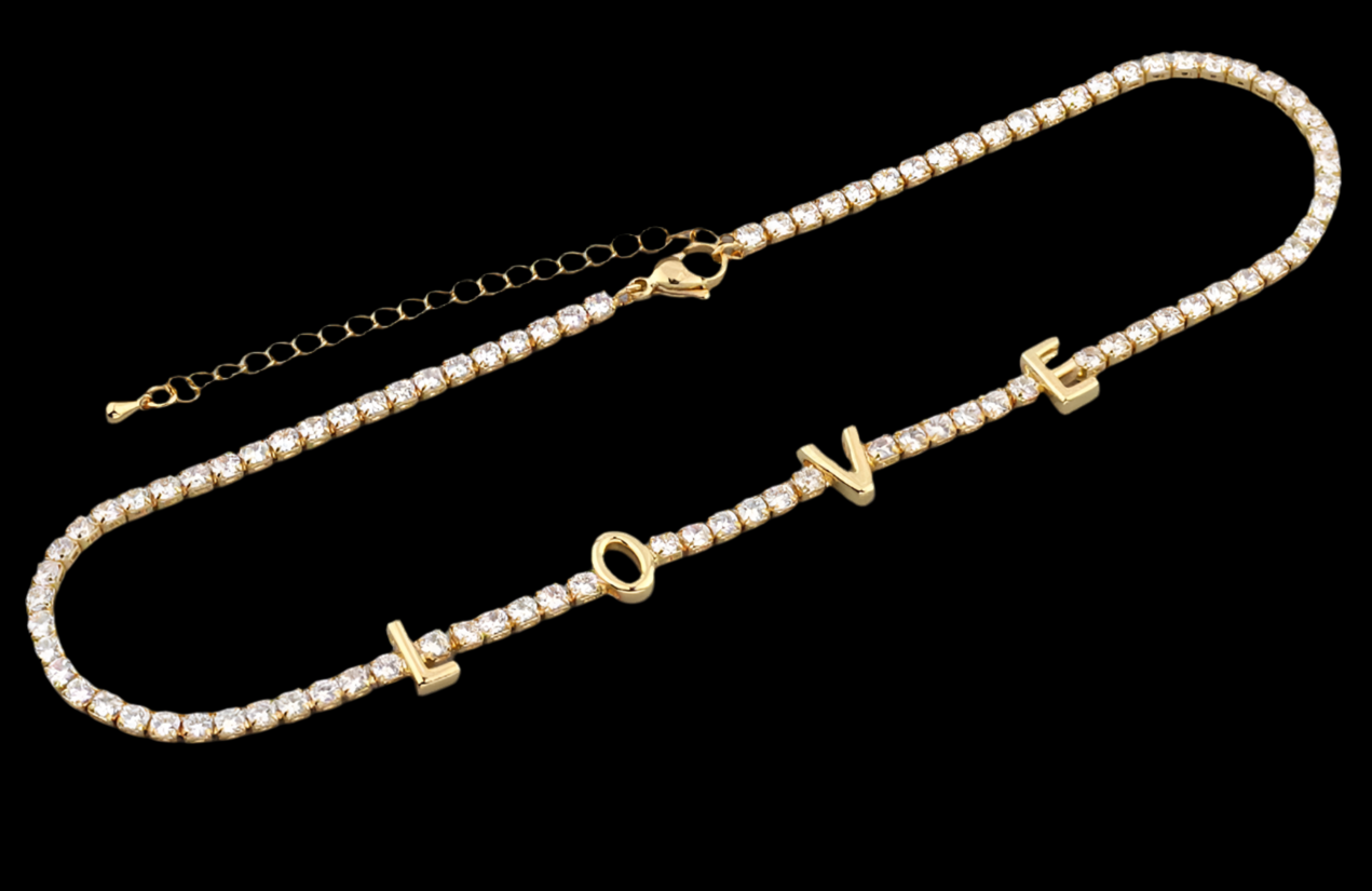Gold necklace with 'LOVE' and heart symbols on a black background