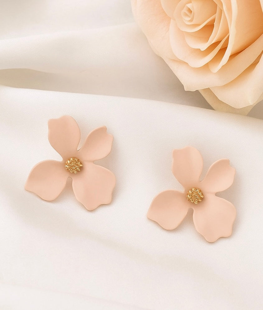 Pair of blush pink flower-shaped earrings with gold centers on a light background.
