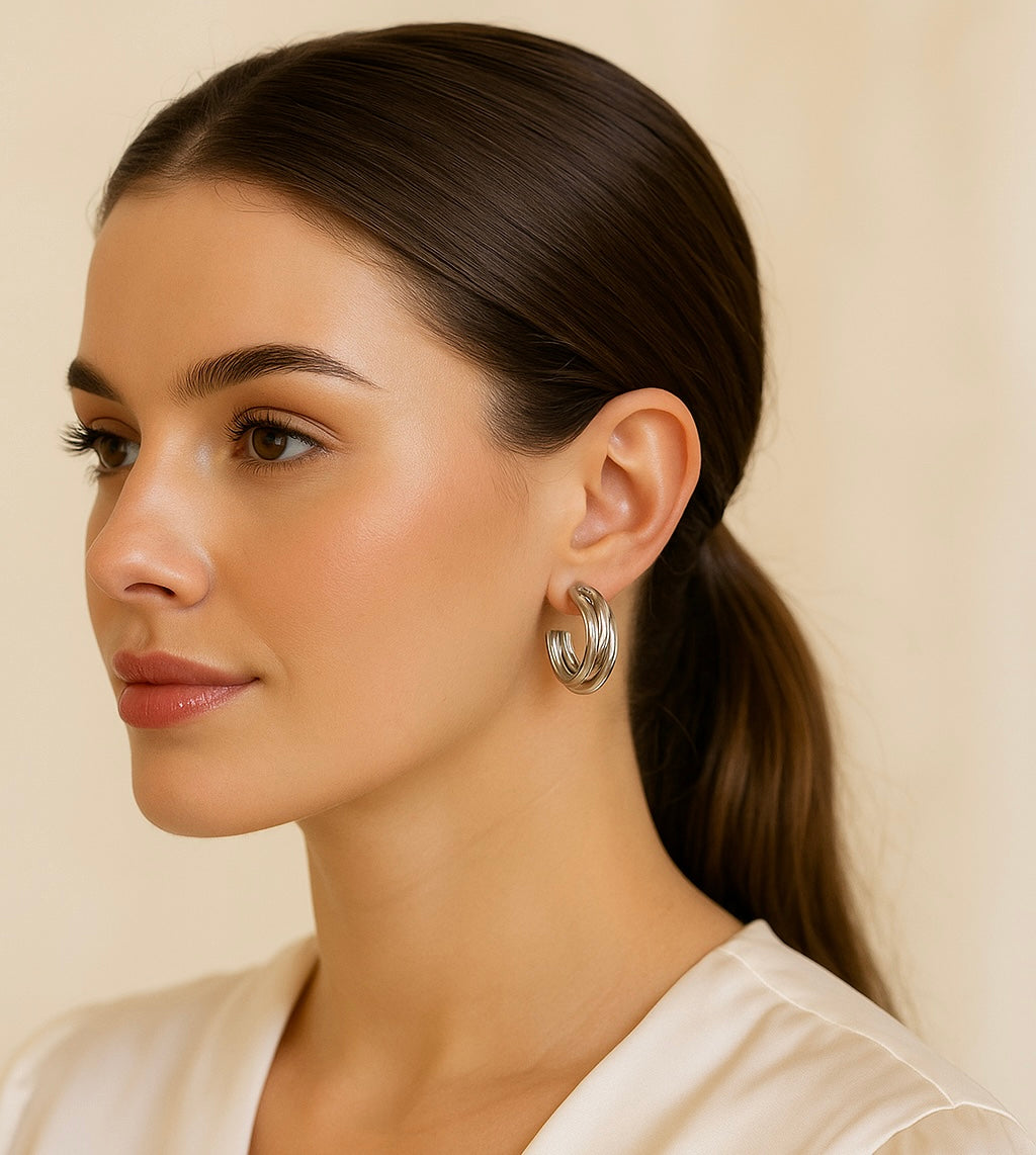 Woman wearing silver hoop earrings against a beige background