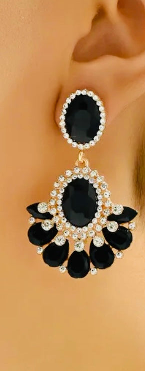 Black and gold earrings worn on an ear with a plain background