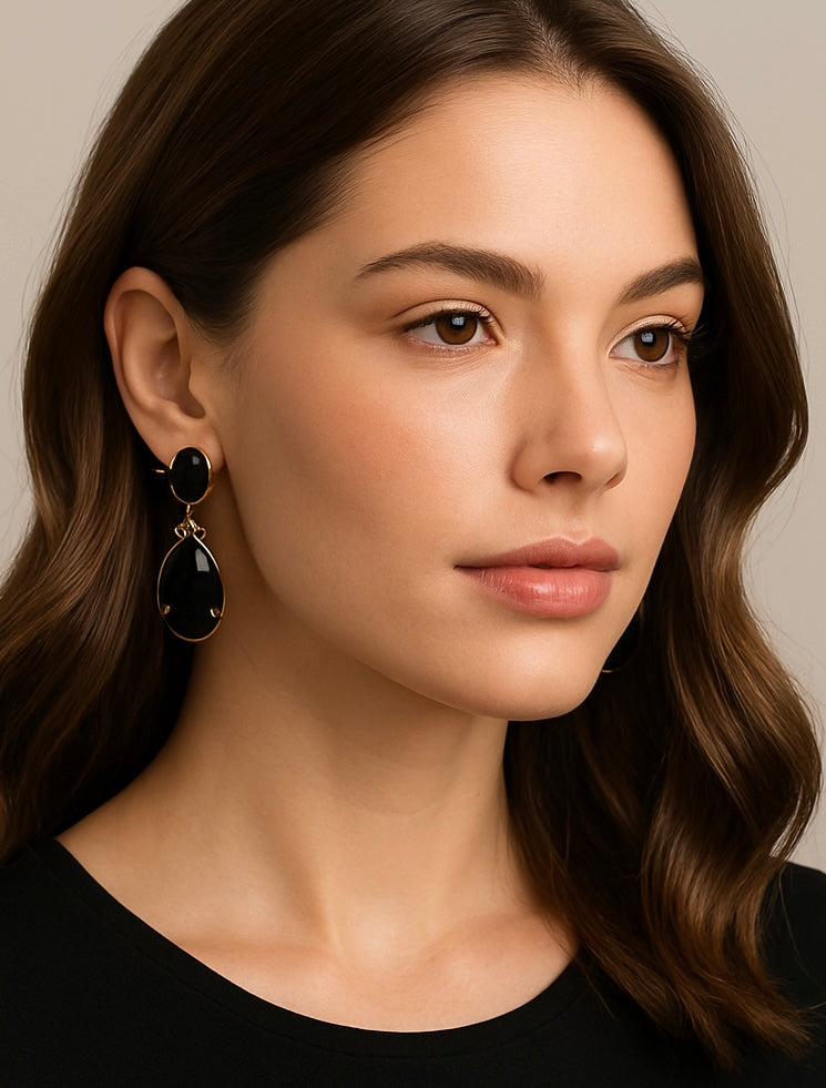 Close-up of a woman wearing black earrings against a neutral background