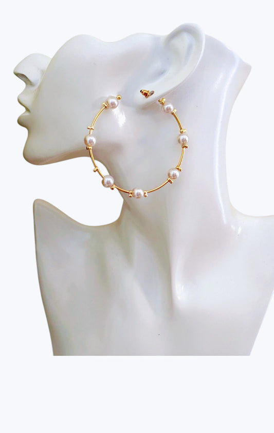 Gold hoop earrings with pearls on a mannequin bust.