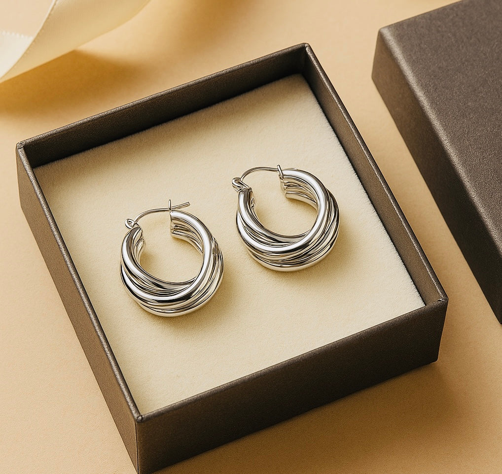 Silver hoop earrings in a box on a beige background