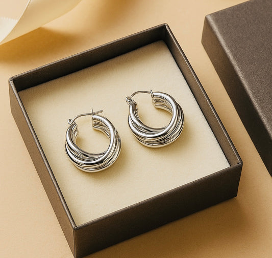 Silver hoop earrings in a box on a beige background