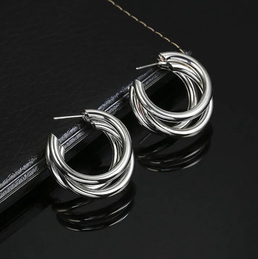 Silver hoop earrings on a black leather surface