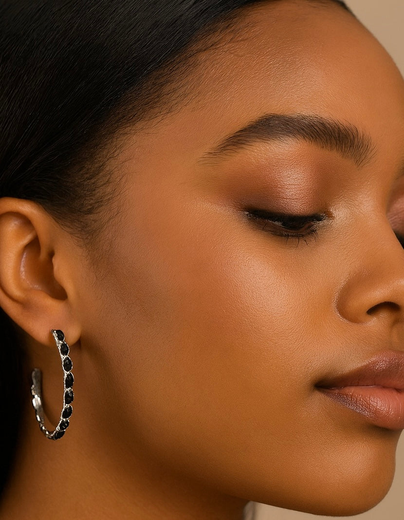 Close-up of a woman wearing a black hoop earring on a neutral background