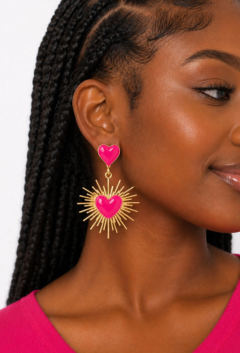 Woman wearing pink heart earrings with gold accents on a white background