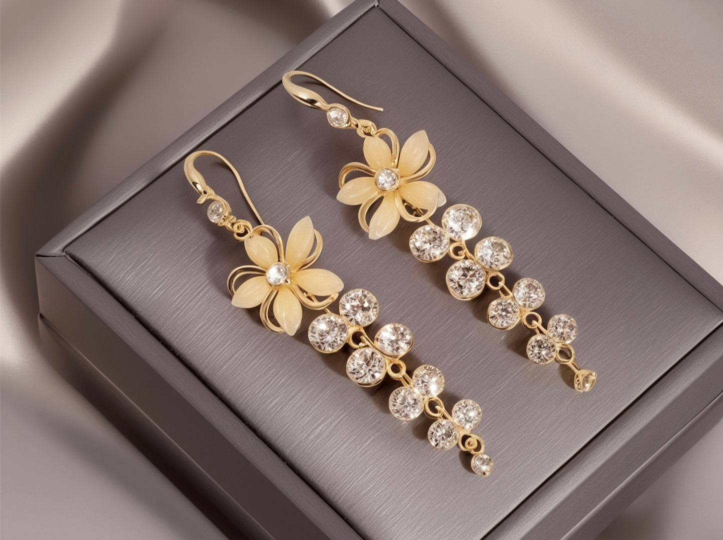Gold floral earrings with clear stones on a gray jewelry box