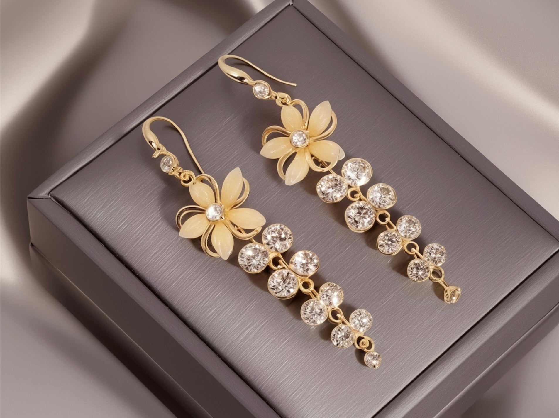 Gold floral earrings with clear stones on a gray jewelry box