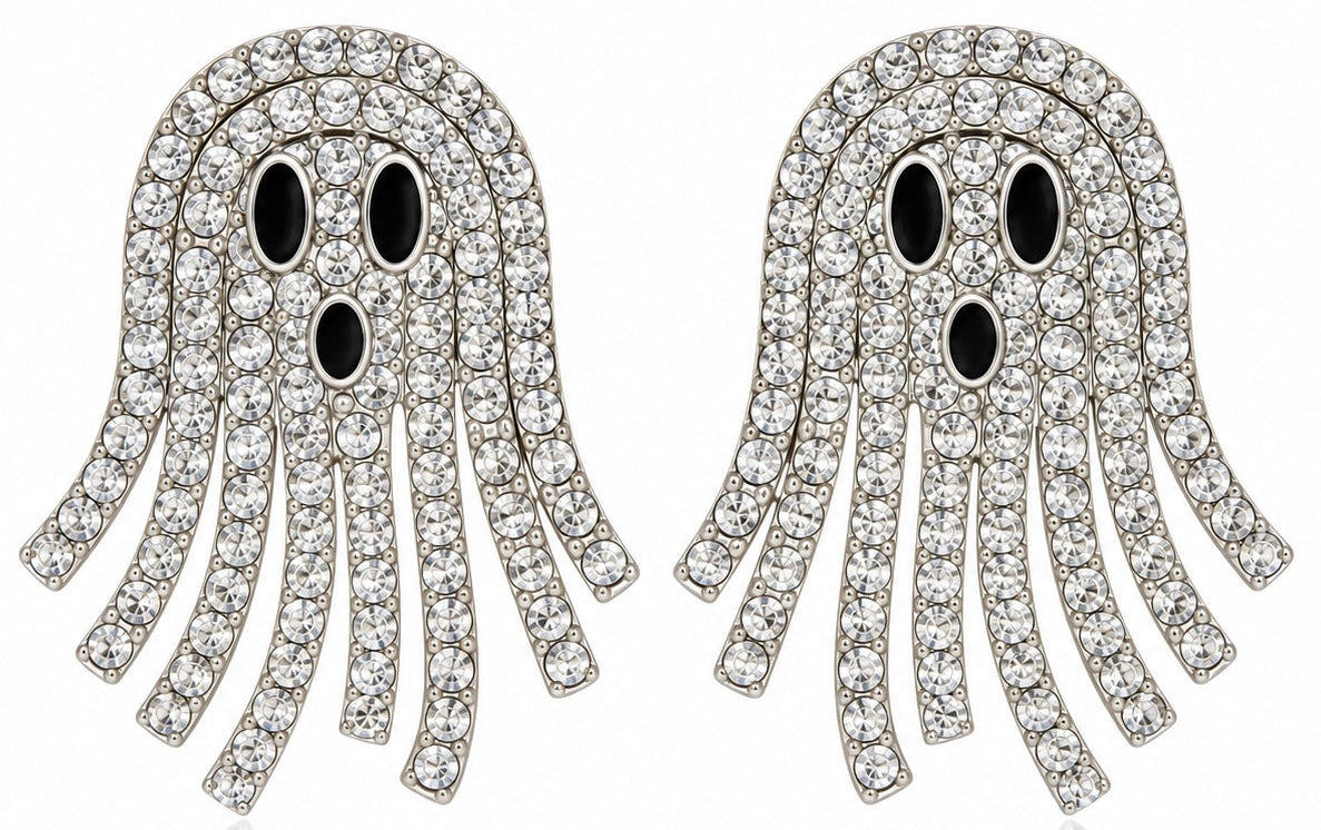 A pair of ghost-shaped stud earrings covered in clear rhinestones with black eyes and mouth, set in silver-toned metal on a white background.