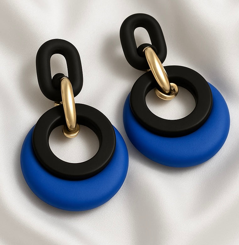 Pair of earrings with black and gold rings and blue circular bases on a white background