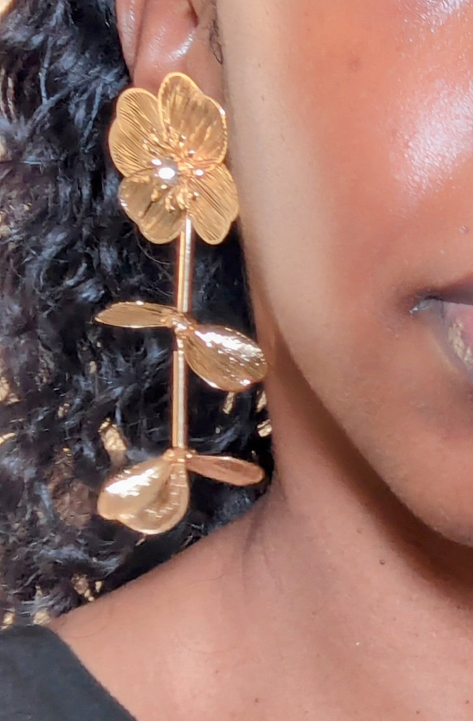 Close-up of a person wearing a gold floral earring.