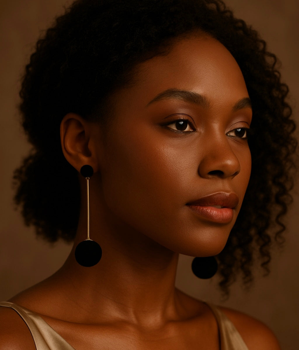 Woman wearing black earrings against a brown background