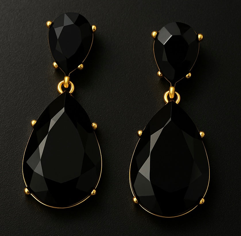 Black teardrop earrings with gold accents on a black background