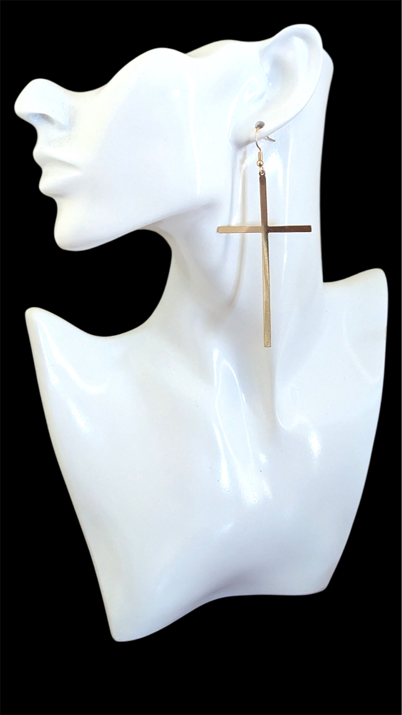 Gold cross earring on a white mannequin bust against a black background