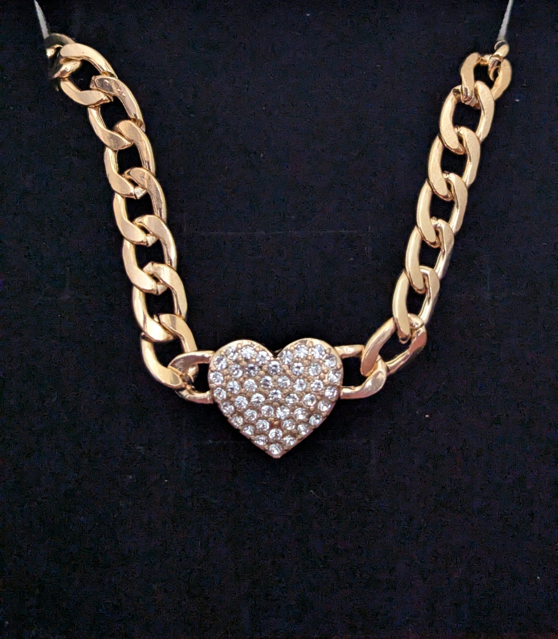 Gold chain necklace with a heart-shaped pendant on a black background