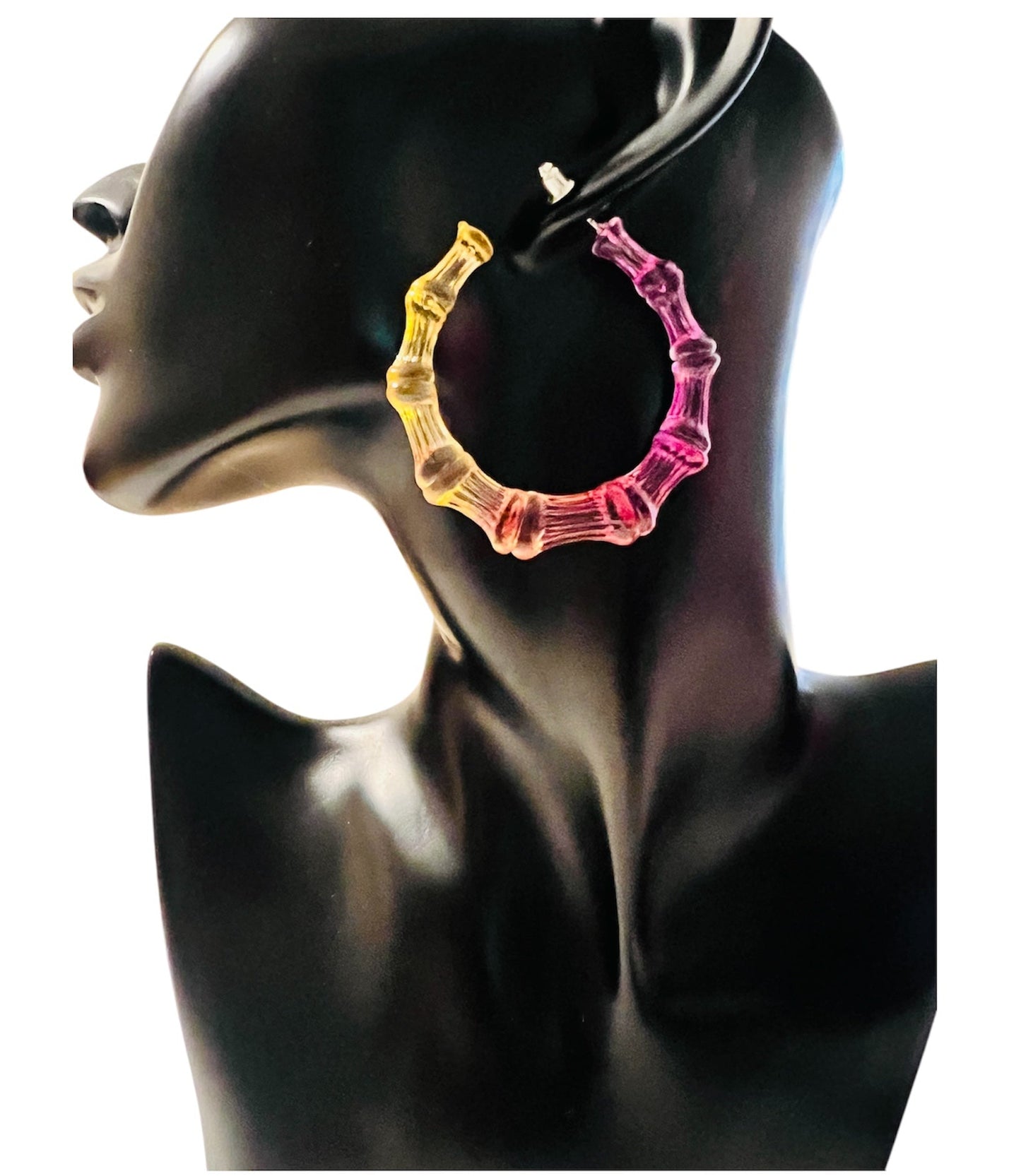 Colorful hoop earrings on a black mannequin head.