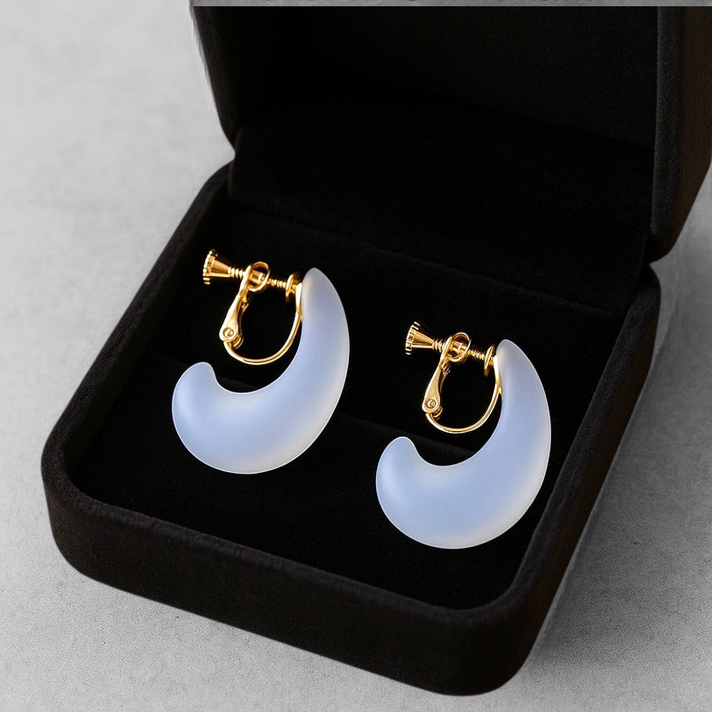 Pair of white crescent moon-shaped earrings with gold accents in a black jewelry box.