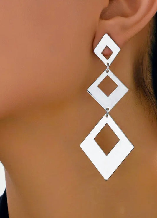 White geometric earrings on a model's ear