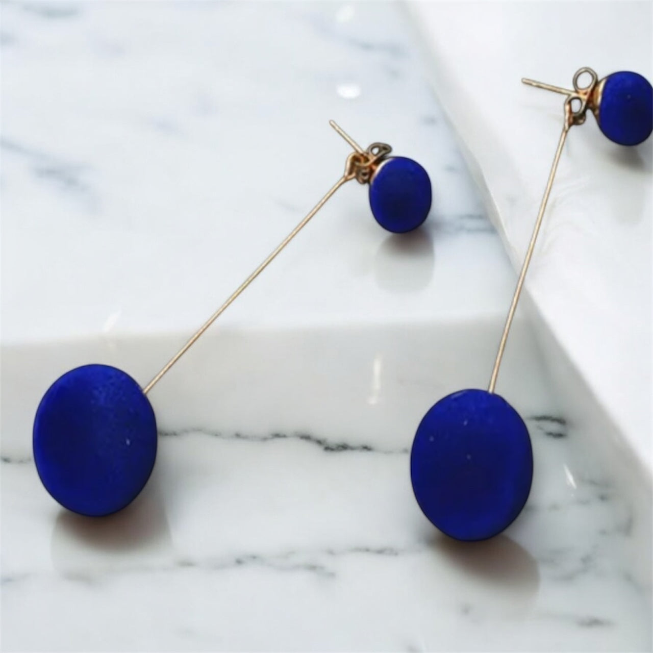 Blue earrings on a marble surface