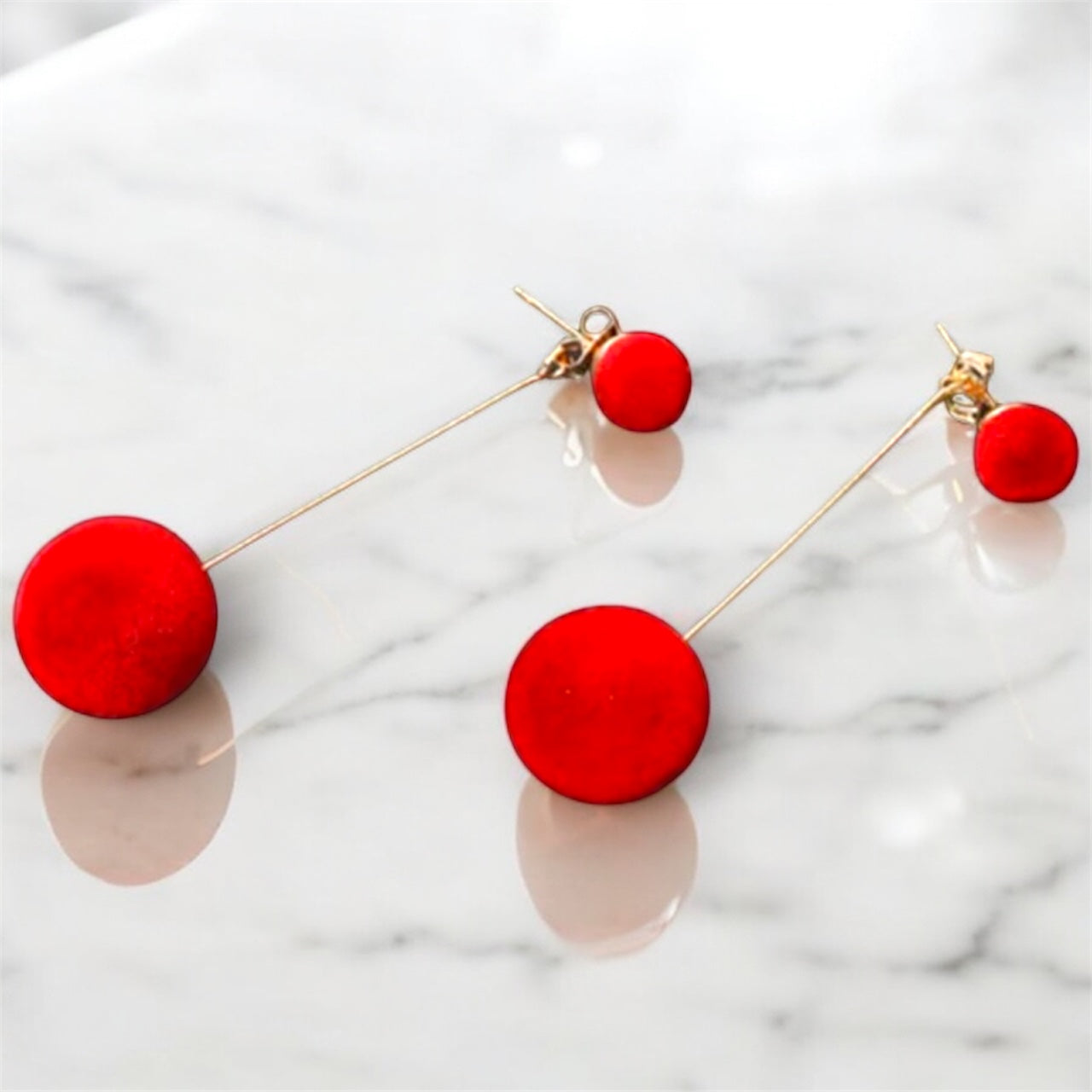 Red circular earrings on a marble background
