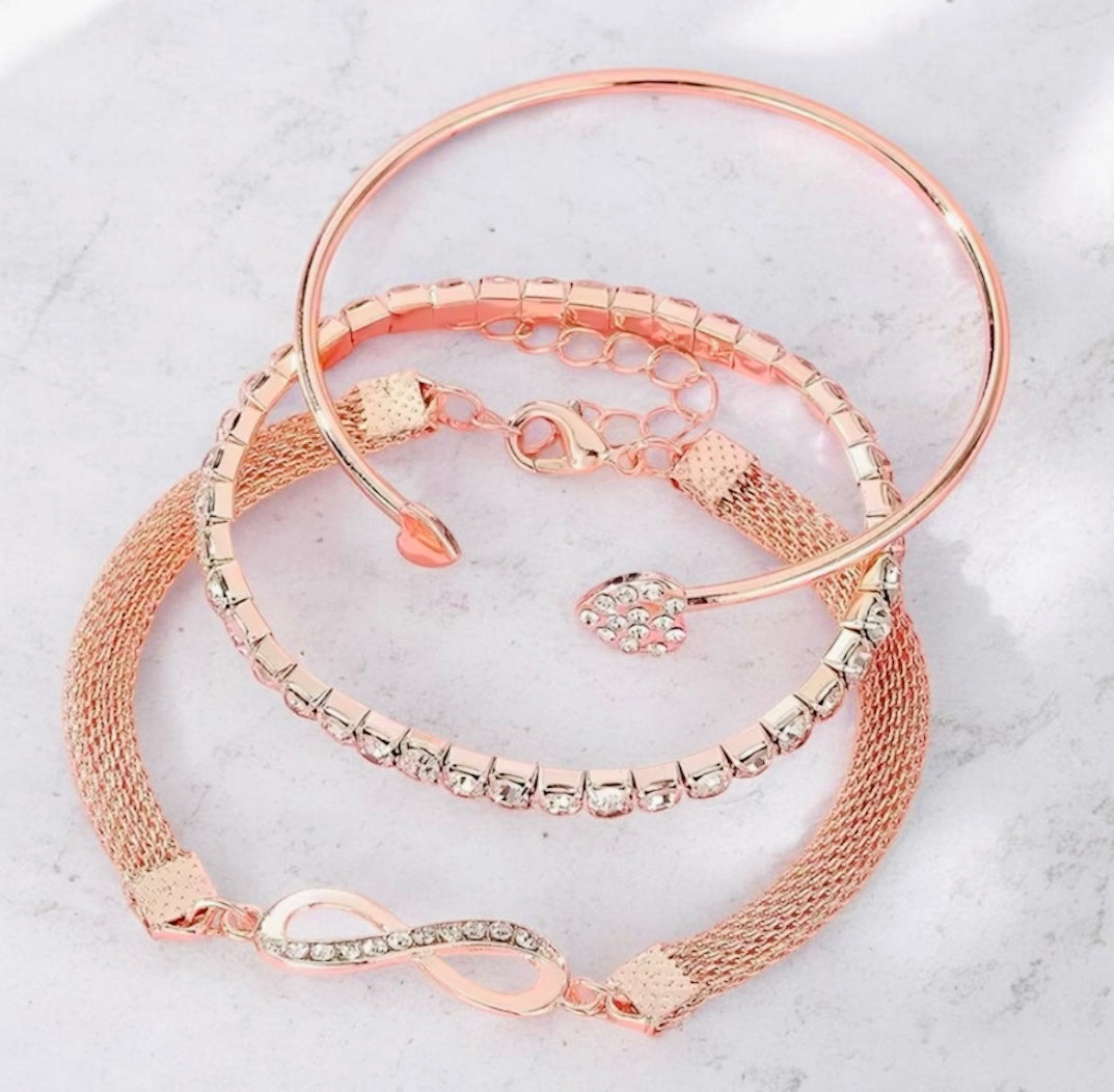 Set of rose gold bracelets on a light gray surface