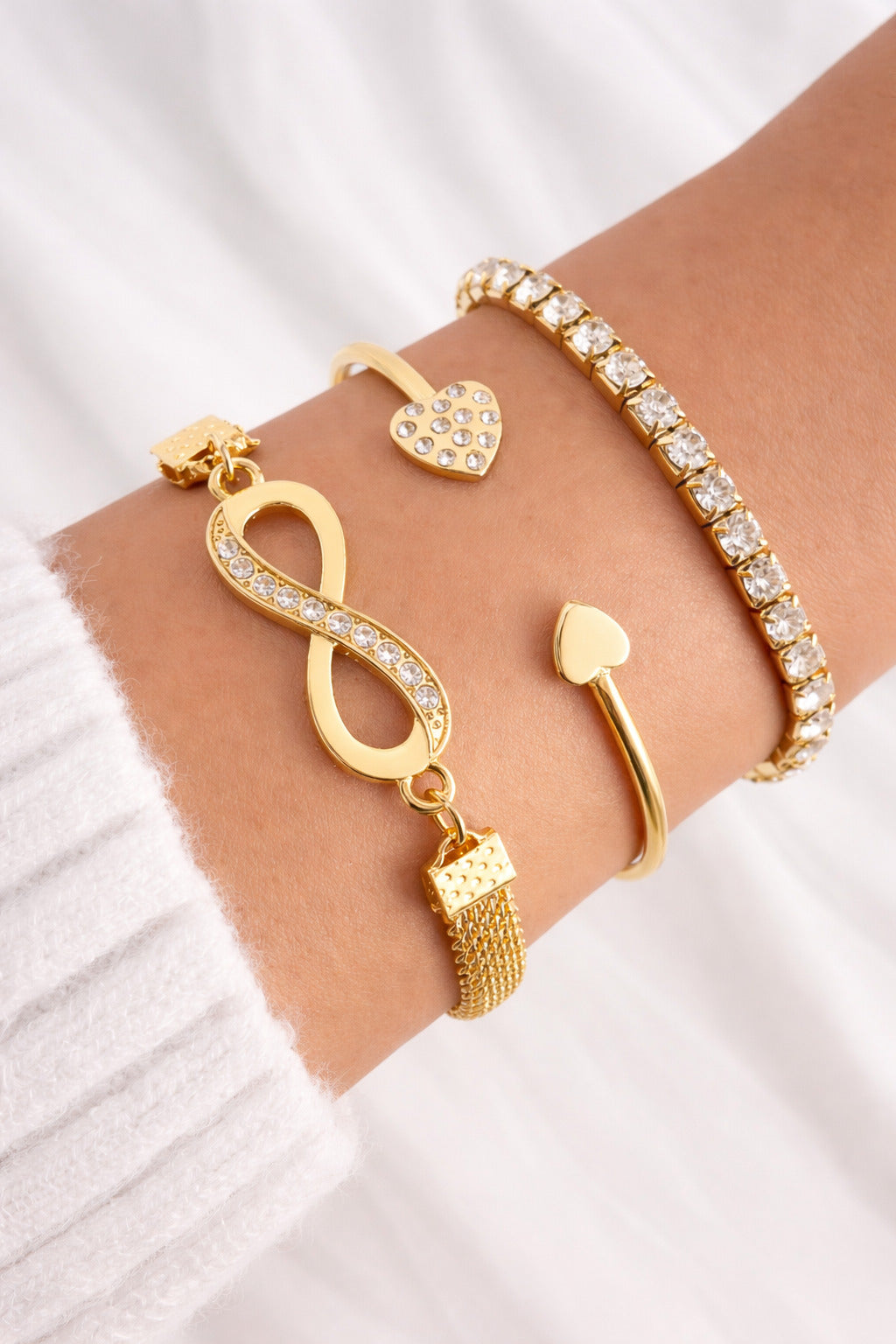 Gold bracelet with heart charm on a wrist against a white background