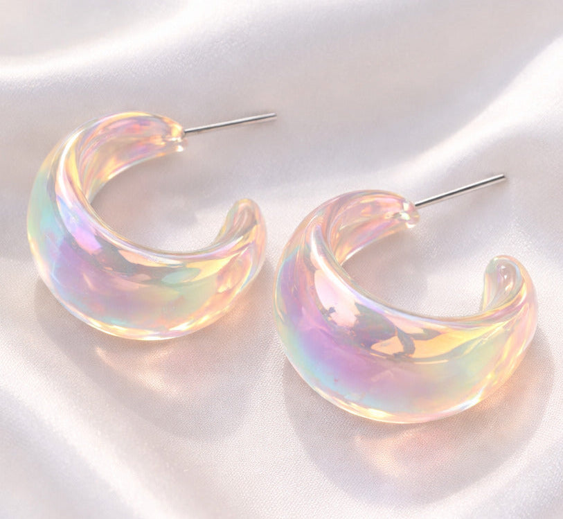 Iridescent hoop earrings on a white fabric background
