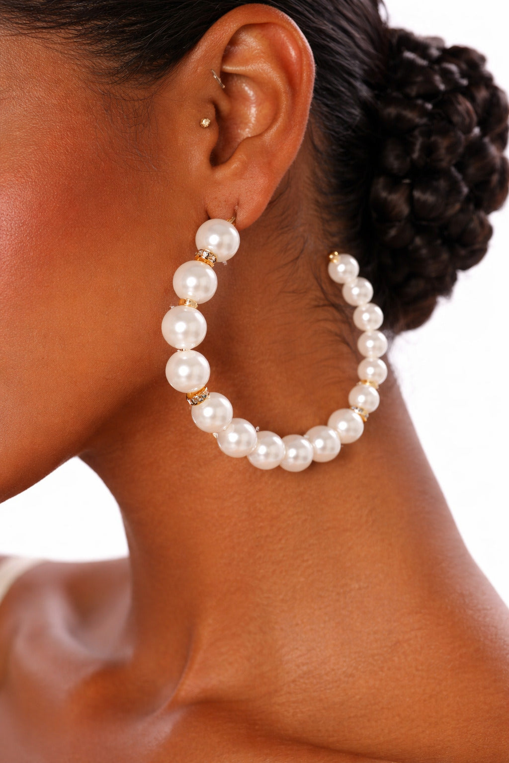 Pearl hoop earrings worn by a person with a white background