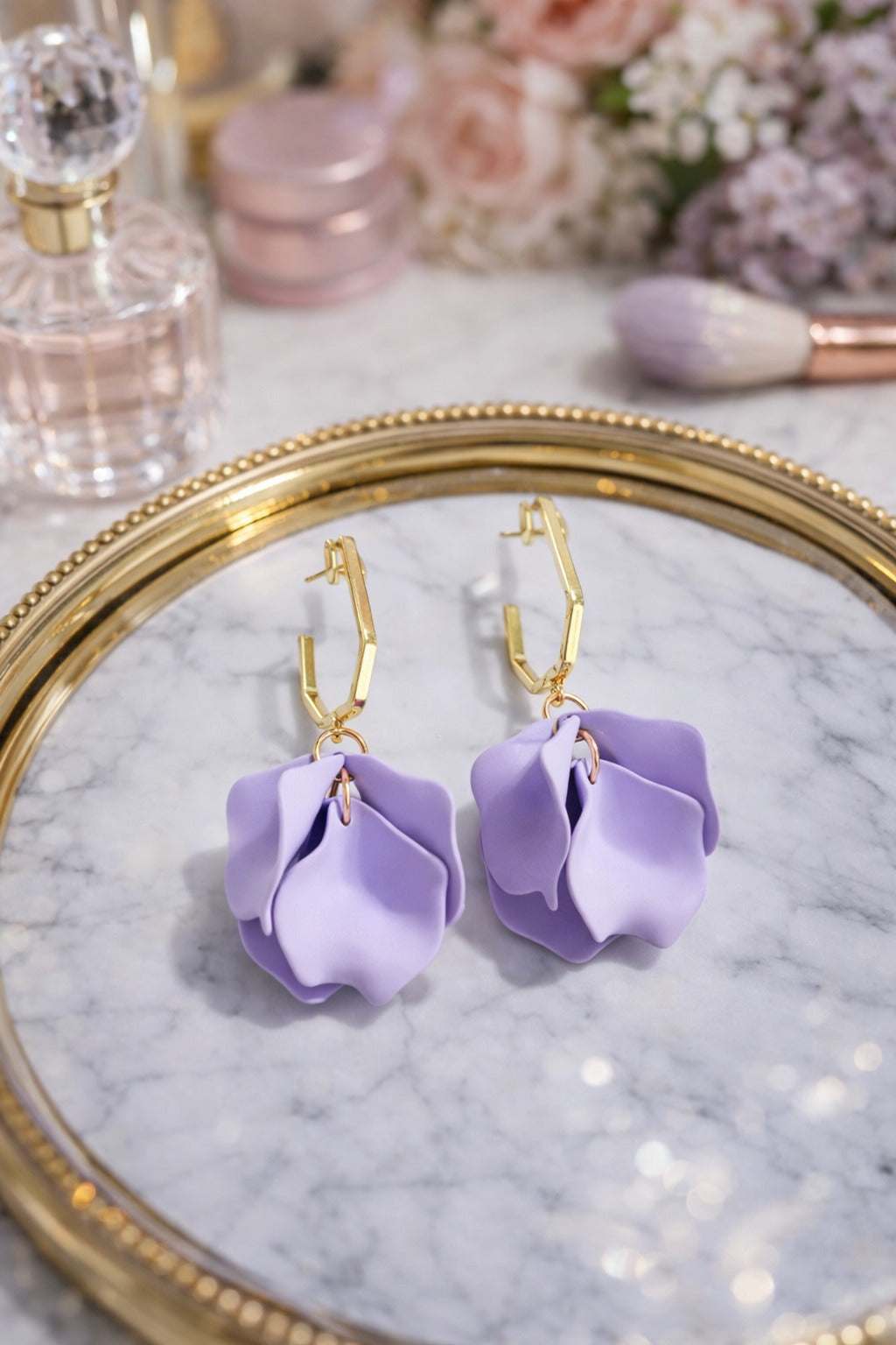 Purple flower-shaped earrings on a marble surface with a gold frame.