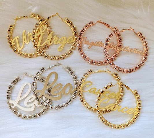 Set of gold and rose gold hoop earrings with zodiac signs on a white background