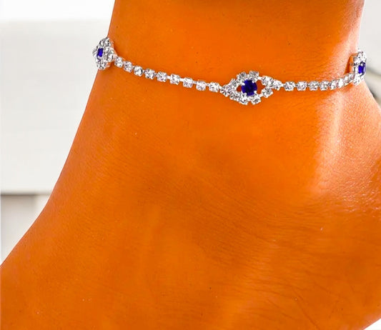 Silver anklet with blue stones on a foot against a white background