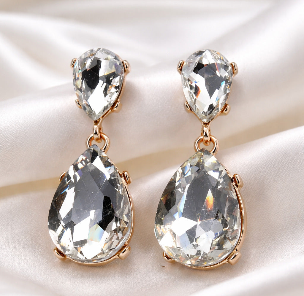 Teardrop-shaped crystal earrings with rose gold accents on a satin surface