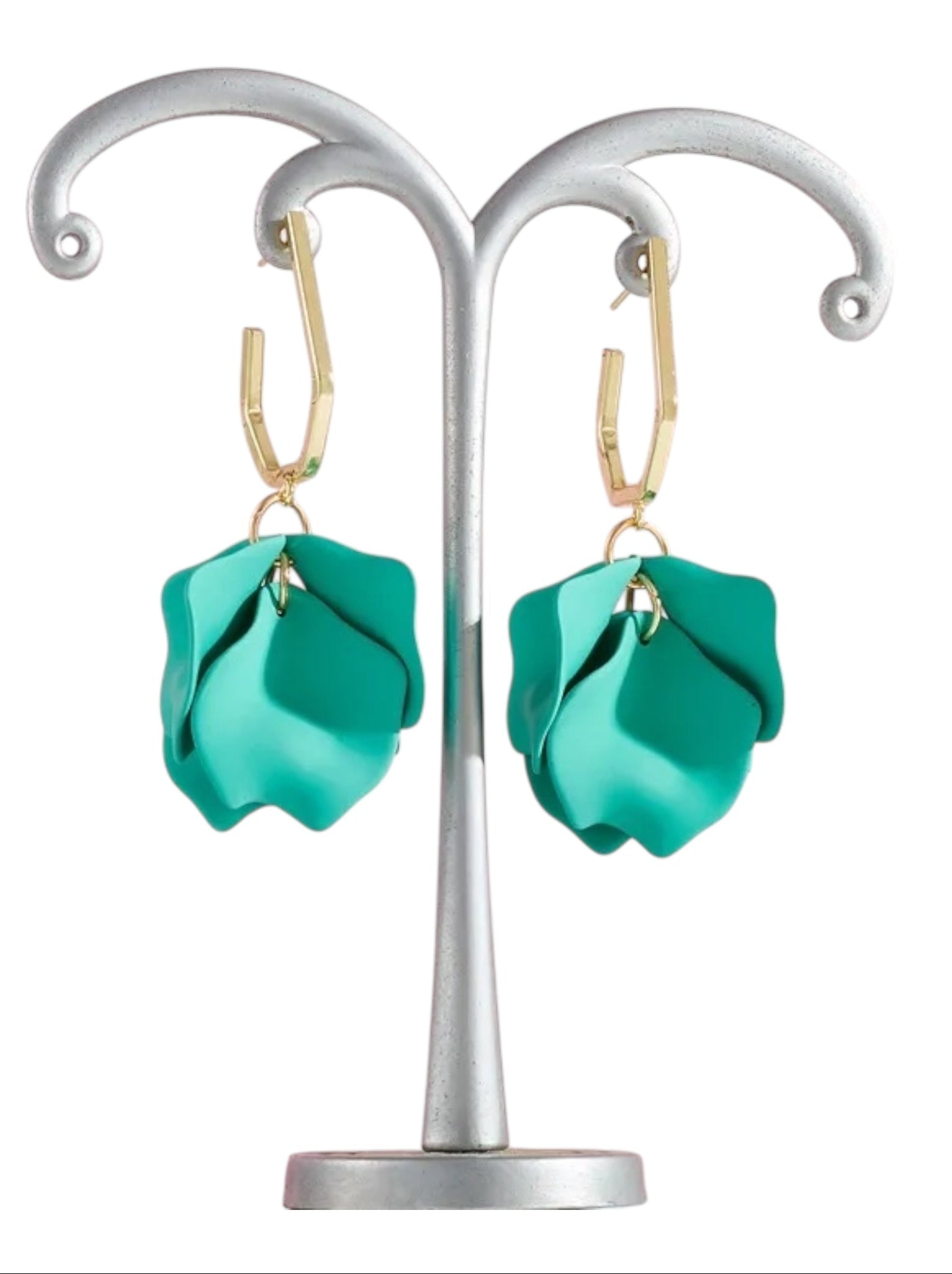 Turquoise earrings on a silver earring stand against a white background