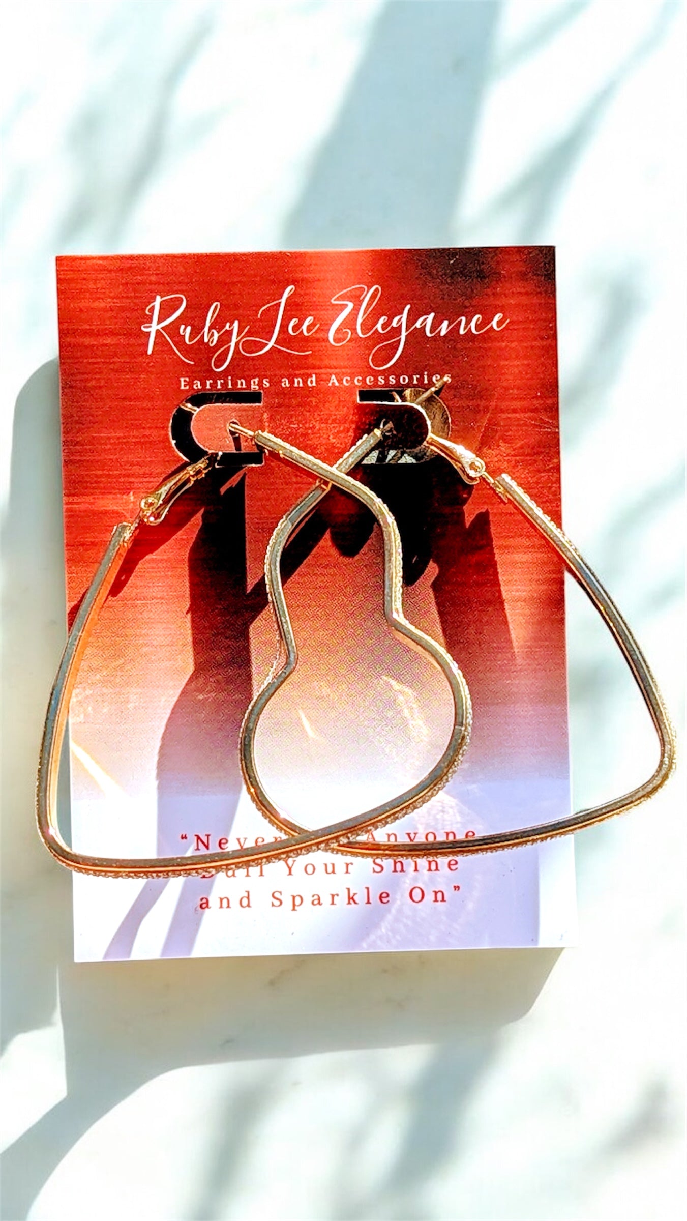 Gold hoop earrings on a Ruby Lee Elegance card with a blurred background