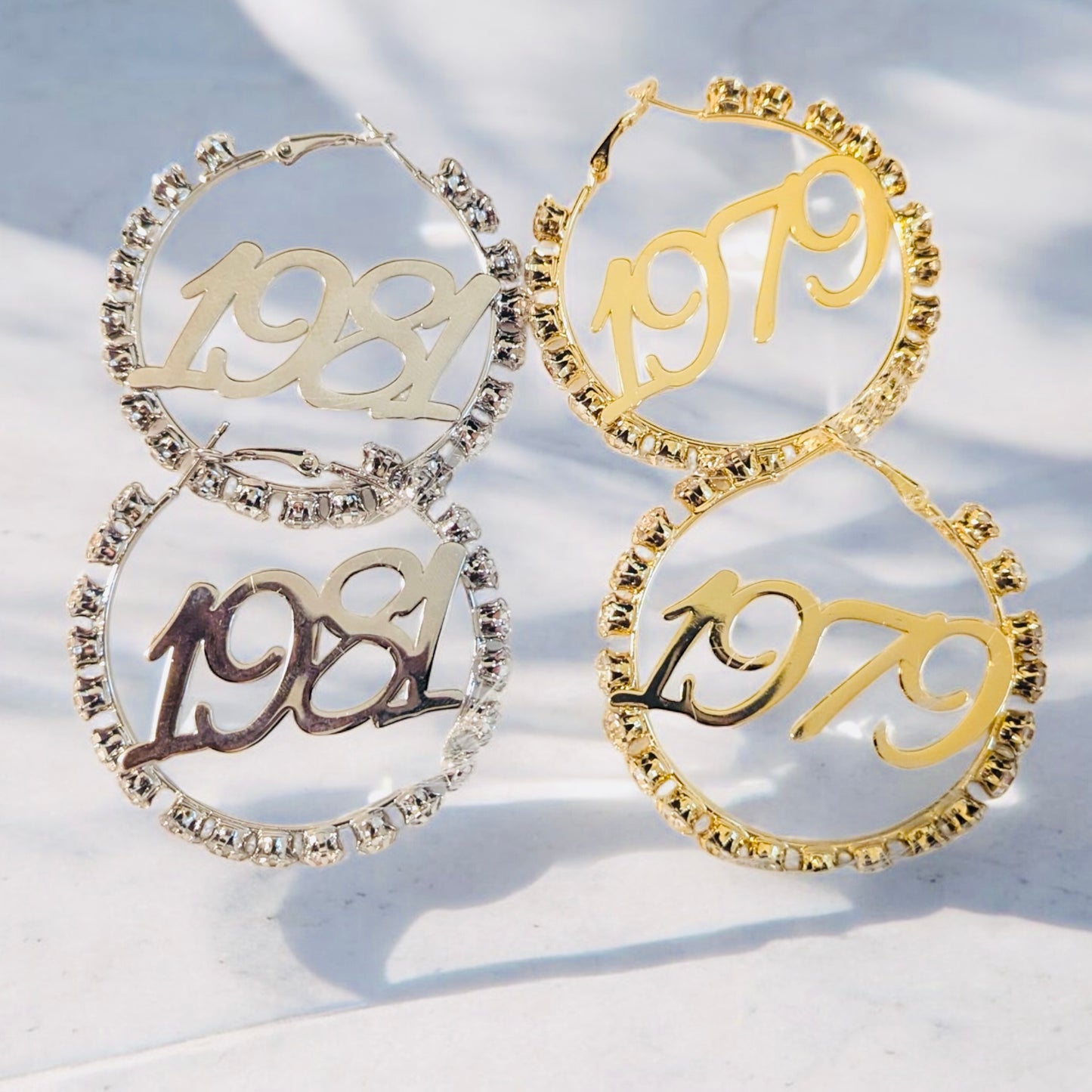 Two pairs of hoop earrings with '1981' and '1979' inscriptions on a light background.