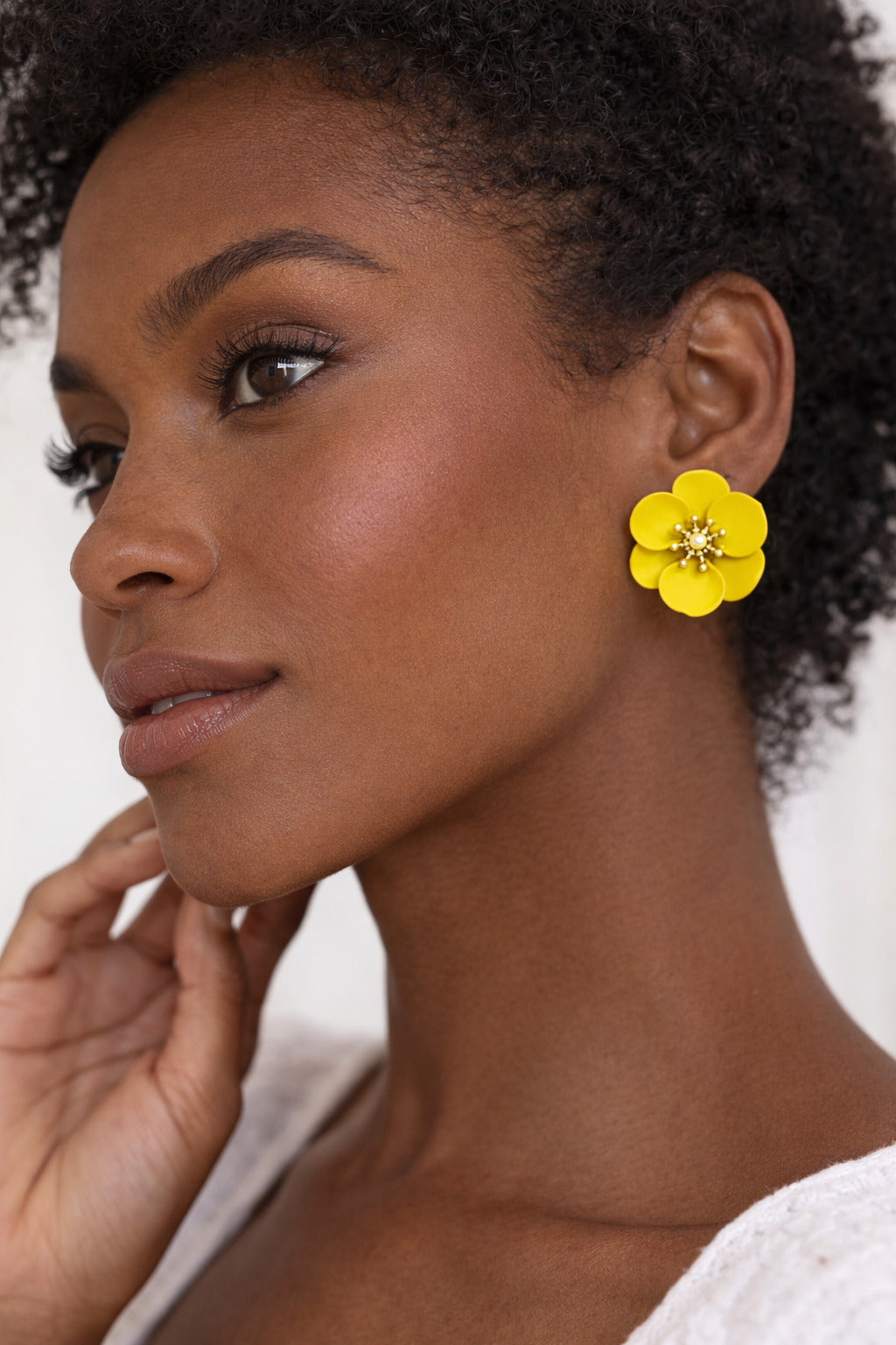 Woman wearing a yellow floral earring against a neutral background
