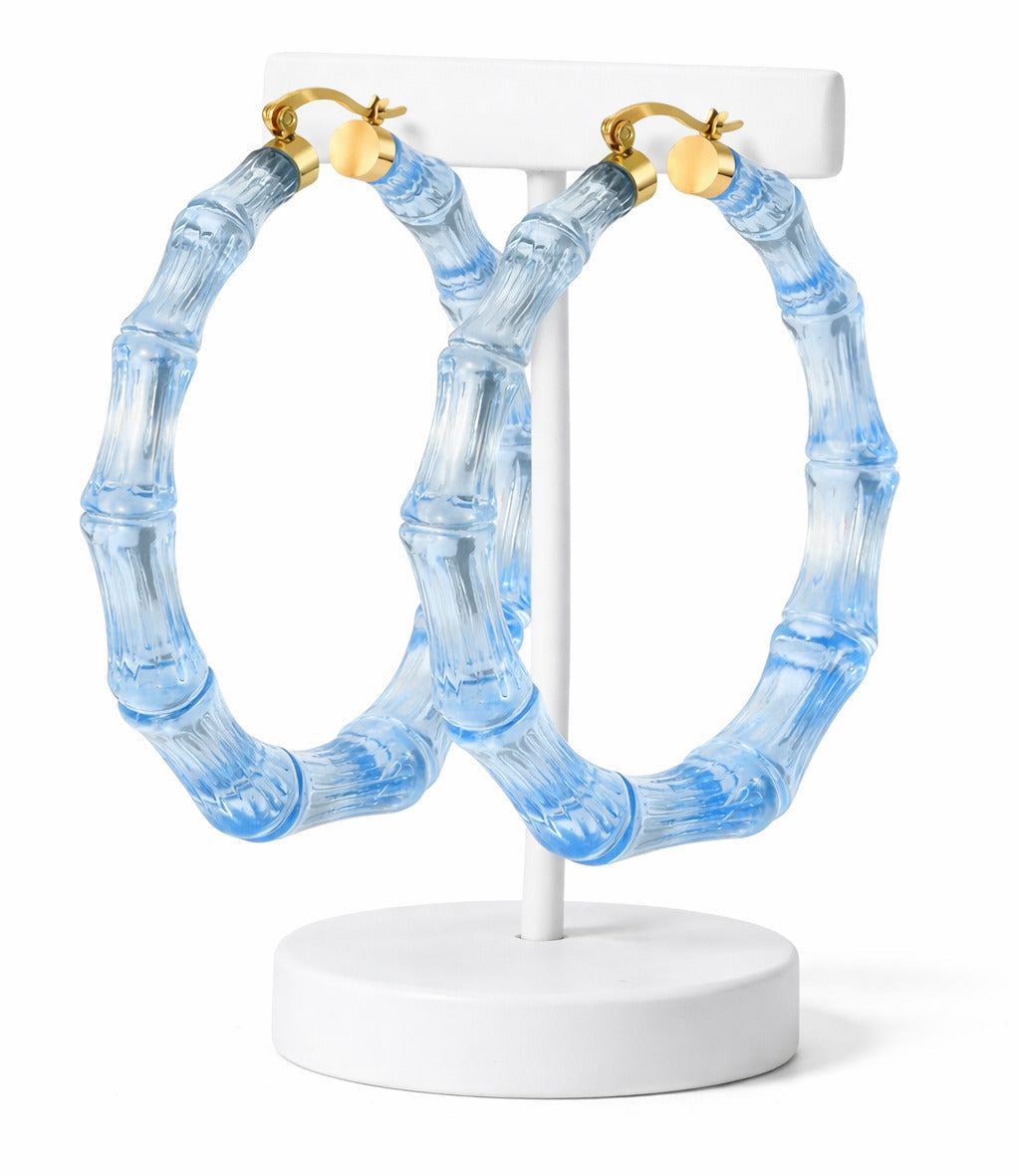 Blue hoop earrings with gold accents on a white stand against a white background