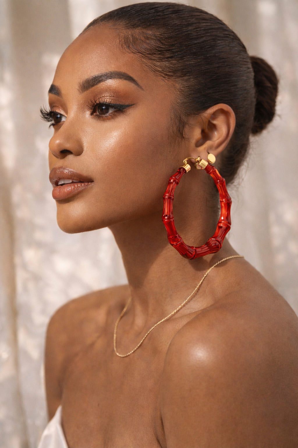 Woman wearing red hoop earrings with a neutral background