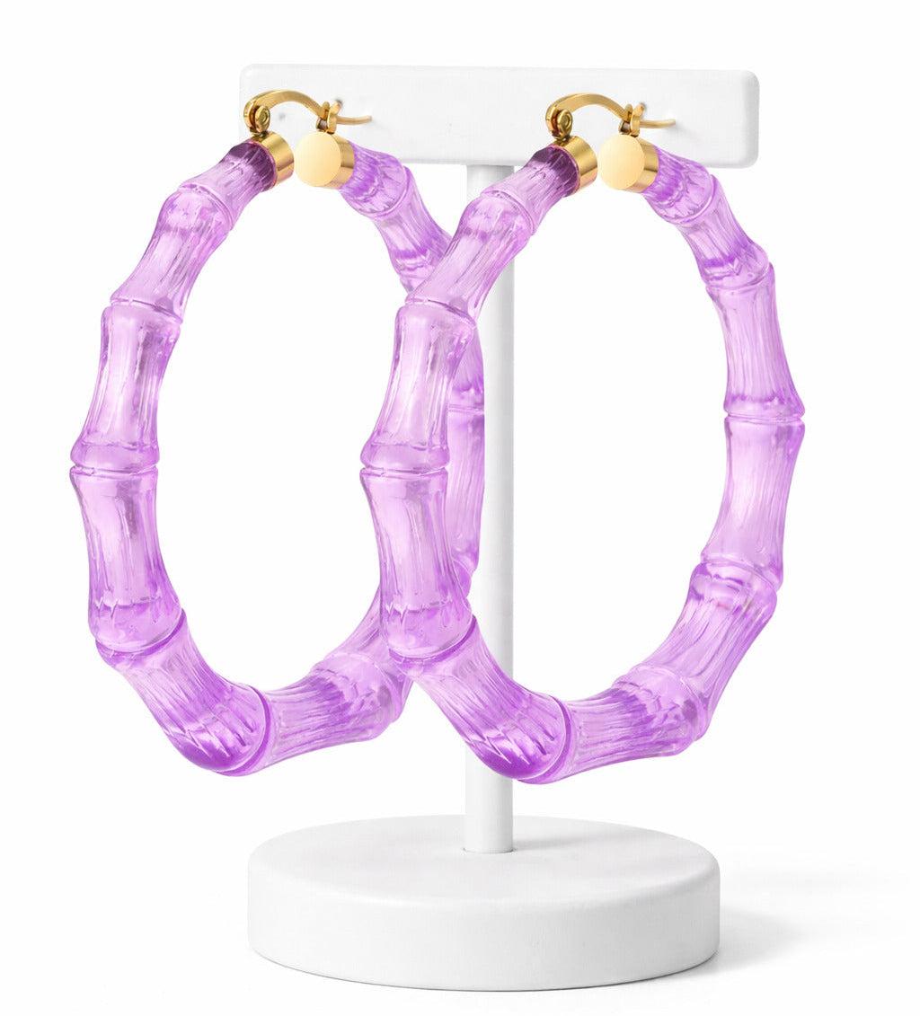 Purple hoop earrings on a white stand against a white background
