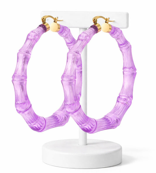 Purple hoop earrings on a white stand against a white background