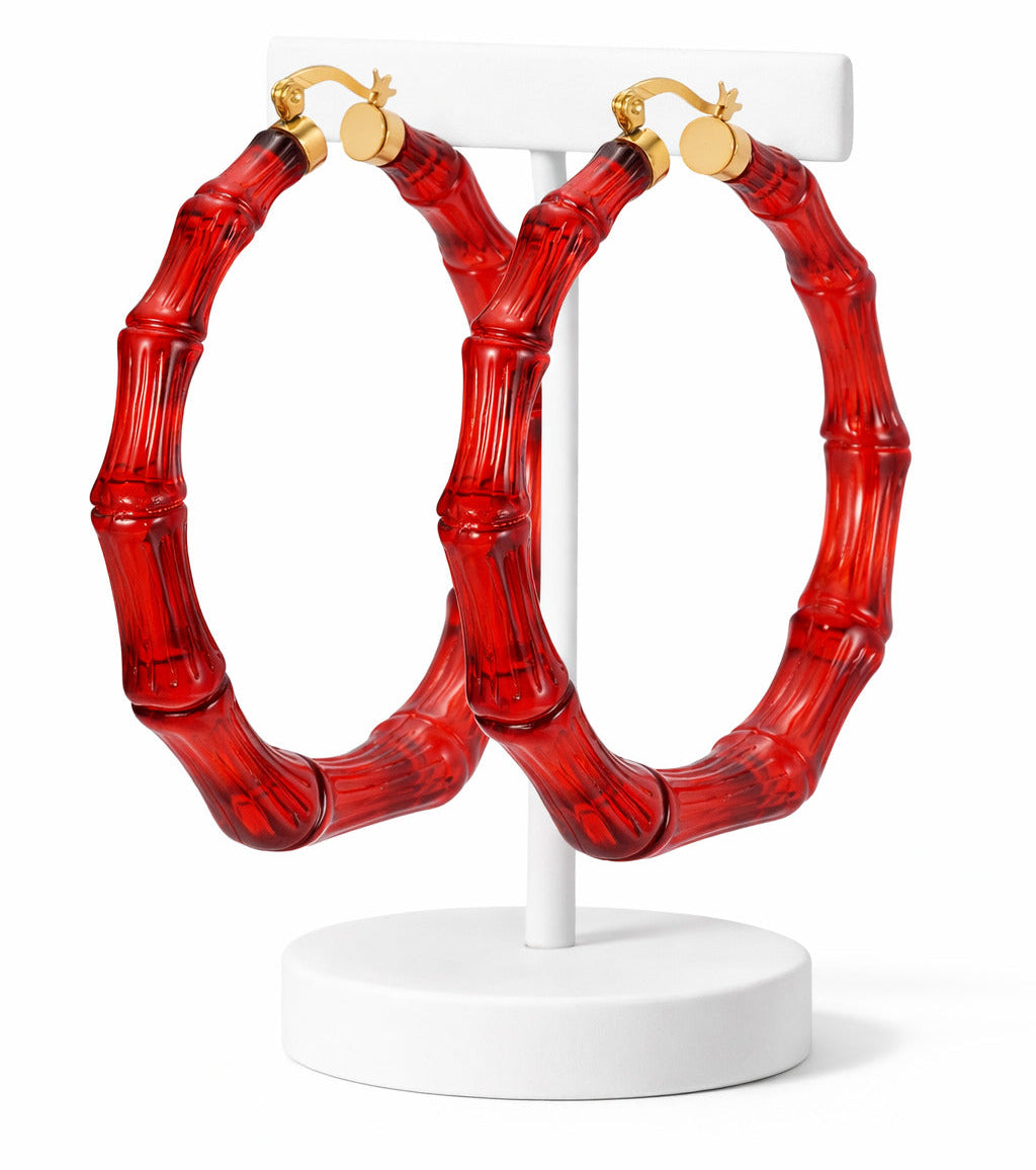 Red bamboo-style hoop earrings on a white stand against a white background