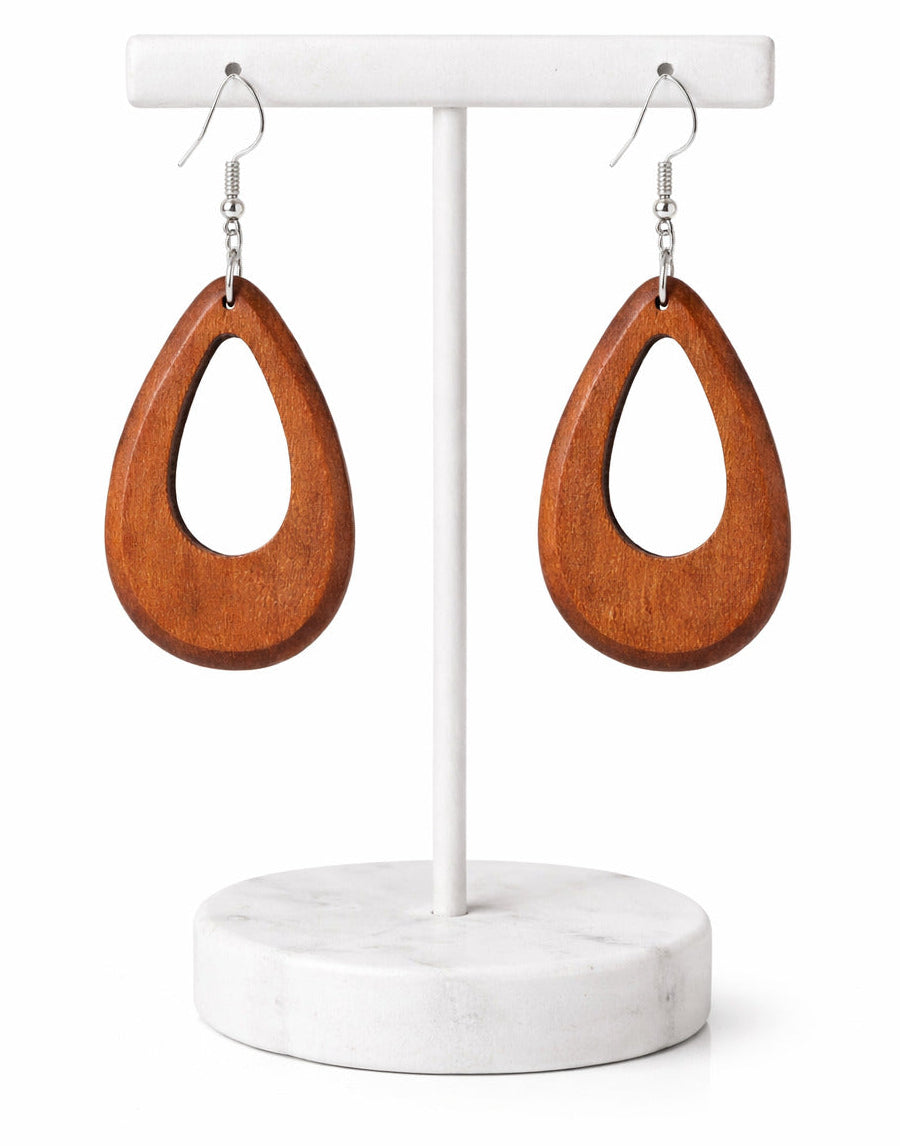 Wooden earrings on a white earring stand with a marble base.