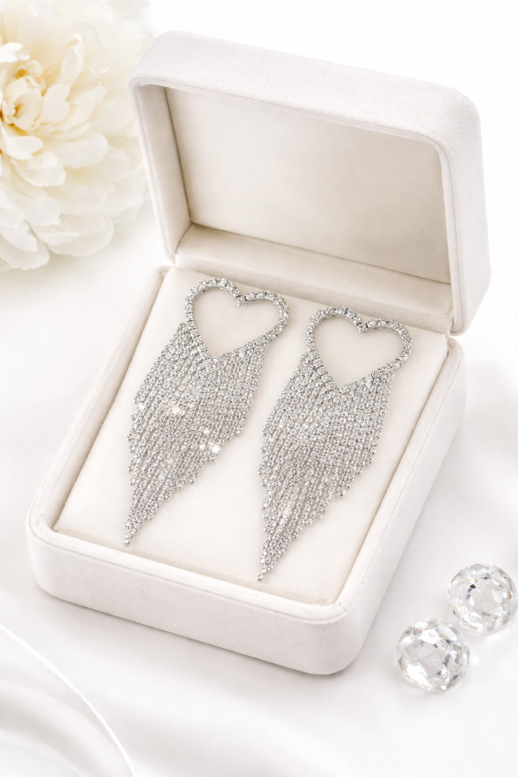Silver fringe earrings in a jewelry box with white flowers in the background