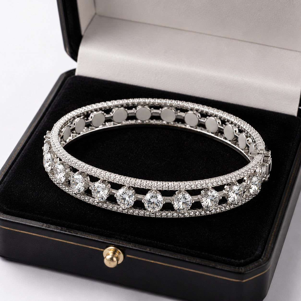 A silver-toned double-row diamond tennis bracelet displayed inside an open black jewelry box with a black velvet lining and a light gray interior.
