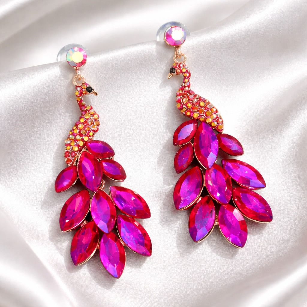 Peacock-shaped earrings with pink and red gemstones on a white background